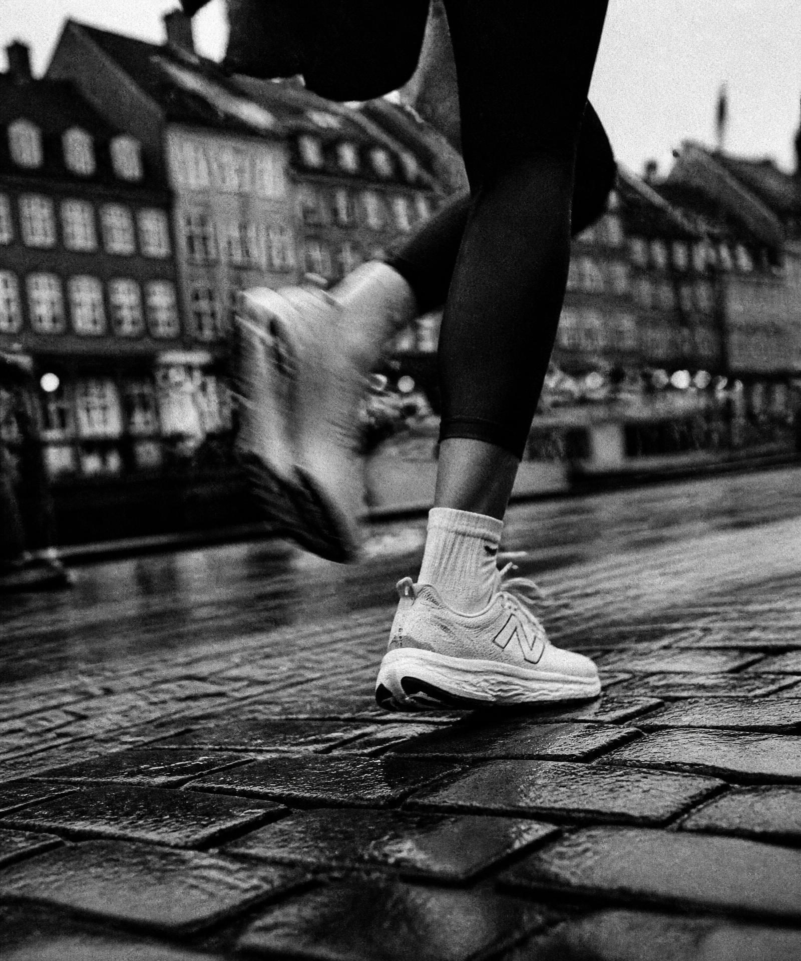 Black and white close-up of a runner's feet in white shoes on Copenhagen asphalt